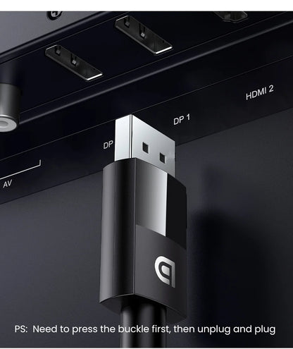 Close-up of a black and silver USB-C cable connector plugged into a dark display panel with HDMI and DP ports visible.