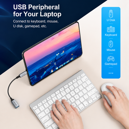 A USB peripheral adapter shown connected to a laptop with a keyboard, mouse, and phone screen, on a beige desk with a blue graphic panel listing supported devices like U Disk, Keyboard, Mouse, and Gamepad.