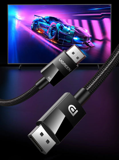 UGREEN HDMI cable shown in a clean product render with two black connector ends and a braided black cable, set against a dark studio background with a TV screen displaying a neon car scene behind it.