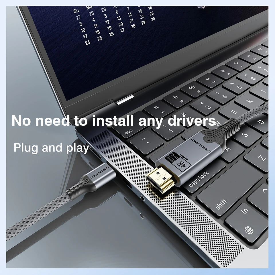 A close-up of a laptop keyboard with a braided USB cable plugged into the side port. The cable has a silver connector and a black-and-silver adapter labeled 'USB 3.
