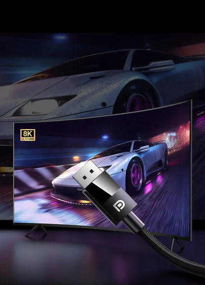 A close-up of a black and silver USB-C cable with a braided black cord, shown in front of a curved monitor displaying a racing car scene. The monitor screen shows an 8K resolution badge, and the background is a dark, moody setting with a blurred sports car.