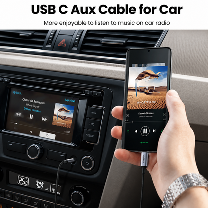 A hand holds a black USB-C aux cable connected to a smartphone, demonstrating car radio music playback. The scene is set inside a car with a dashboard display and the text 'USB C Aux Cable for Car' at the top.