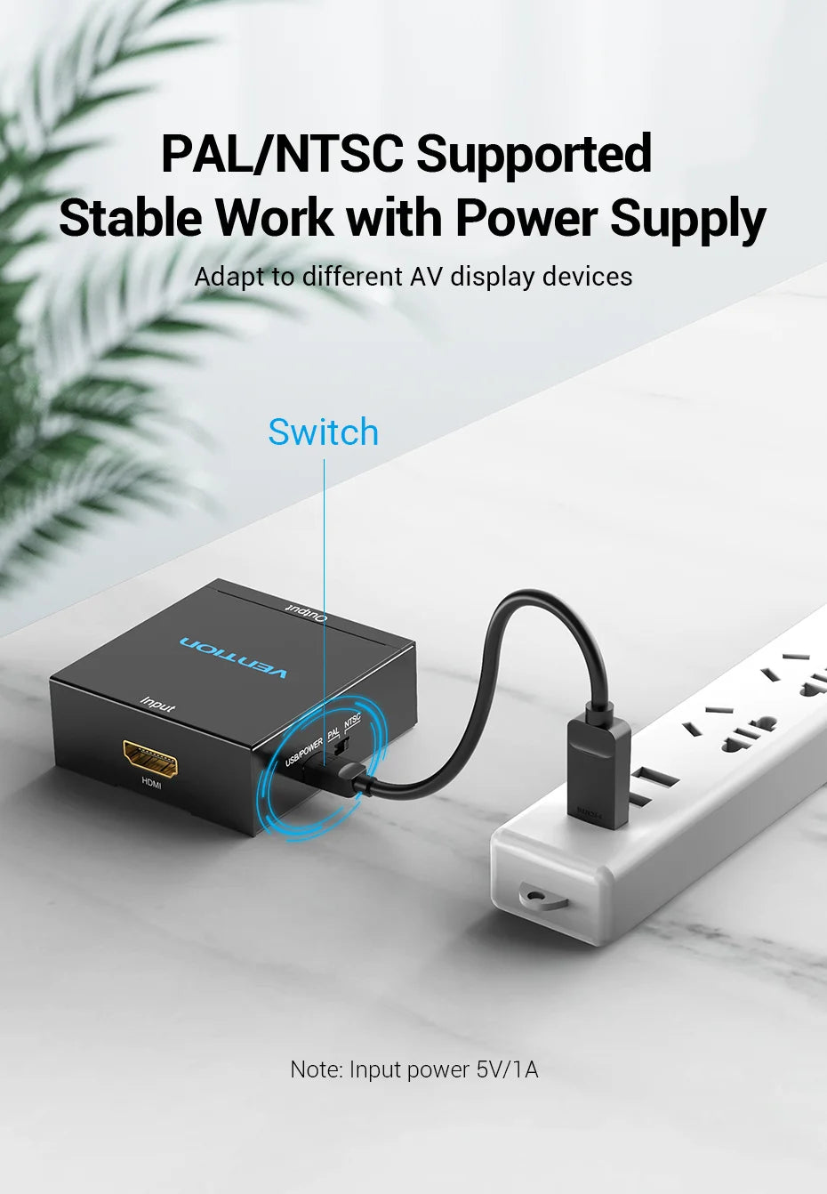 A black Vionix HDMI splitter adapter shown on a light marble surface, connected to a white power strip with a power cord. The image includes text overlays explaining its function as a PAL/NTSC supported stable work with power supply adapter.
