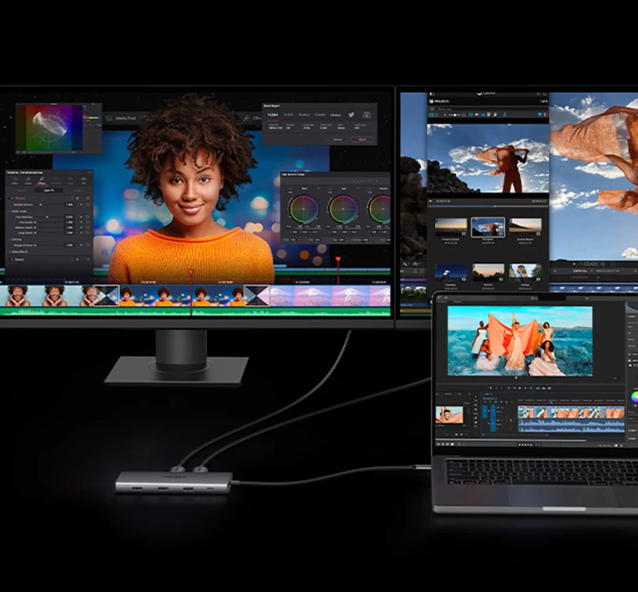 Multiple computer monitors displaying video editing software with a laptop and USB-C hub in the foreground.