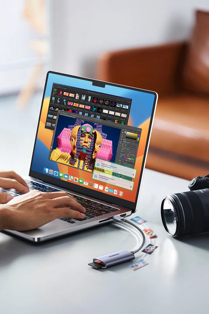 Person using a laptop with a colorful screen, camera, and USB drives on a desk.