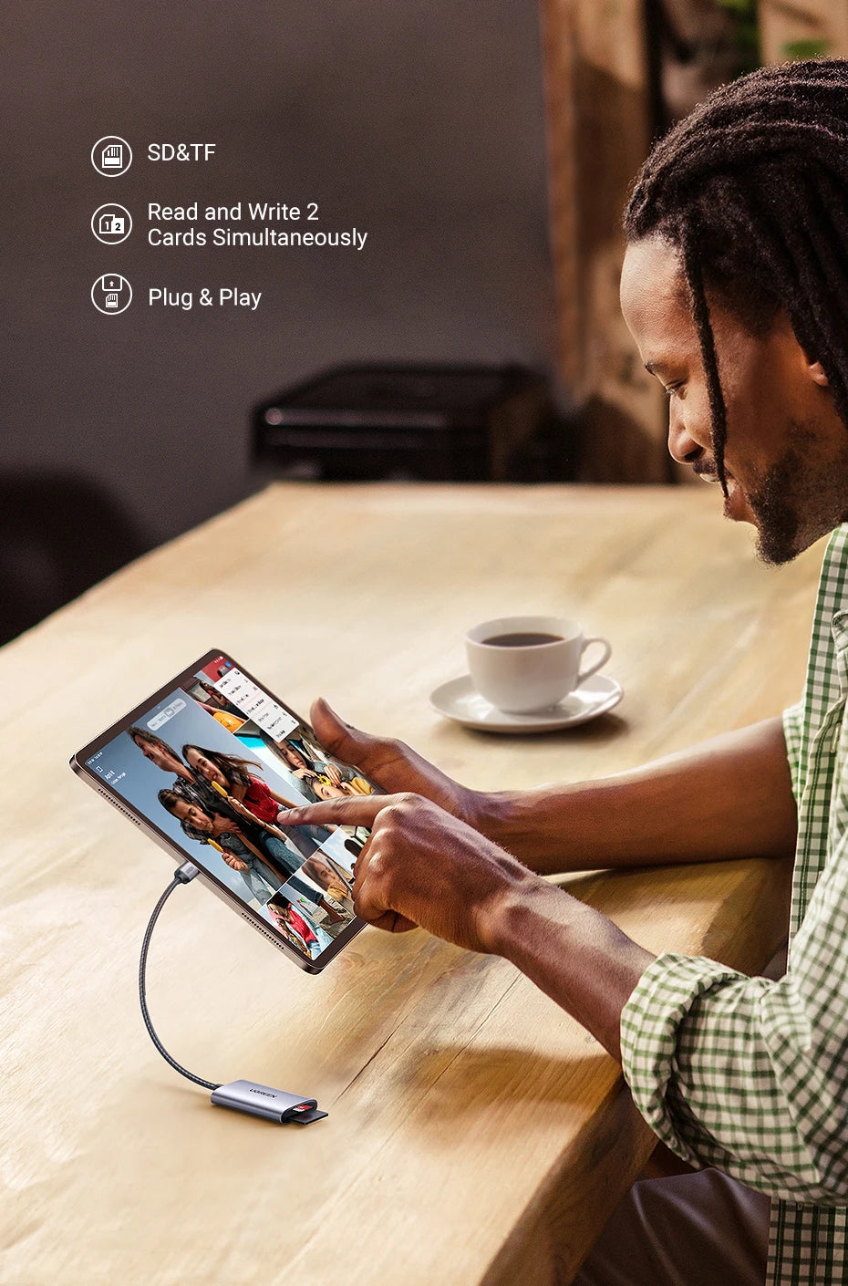 A man seated at a wooden table uses a tablet connected to a USB-C hub device. The scene includes marketing text on the left reading 'SD&TF', 'Read and Write 2 Cards Simultaneously', and 'Plug & Play'.