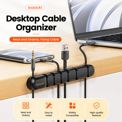 A black Toocki desktop cable organizer mounted on a light wood desk, holding multiple cables including a laptop USB-C connection, a smartphone audio jack, and other cords. The image includes promotional text and feature icons at the top and bottom.