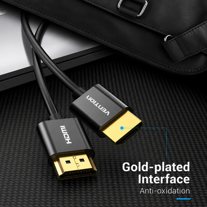 Black HDMI cable with gold-plated interface connectors, shown plugged into a laptop with a black leather bag in the background. Text on the image reads 'Gold-plated Interface Anti-oxidation' and shows brand names 'UNICH' and 'VENTION' on the connectors.