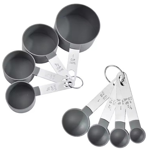 Set of gray measuring cups and spoons with silver handles on a white background