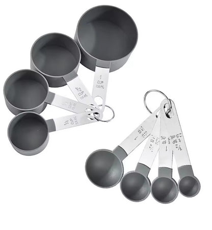 Set of gray measuring cups and spoons with silver handles on a white background