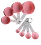 Set of pink measuring spoons on a white background
