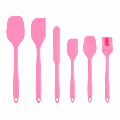 Set of pink silicone spatulas and a brush on a white background